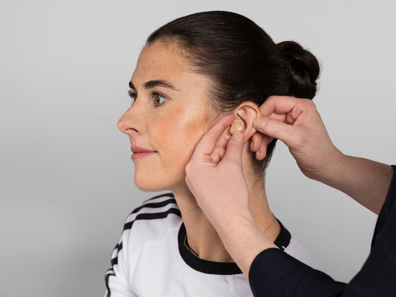 Woman having a small hearing aid fitted to her ear.