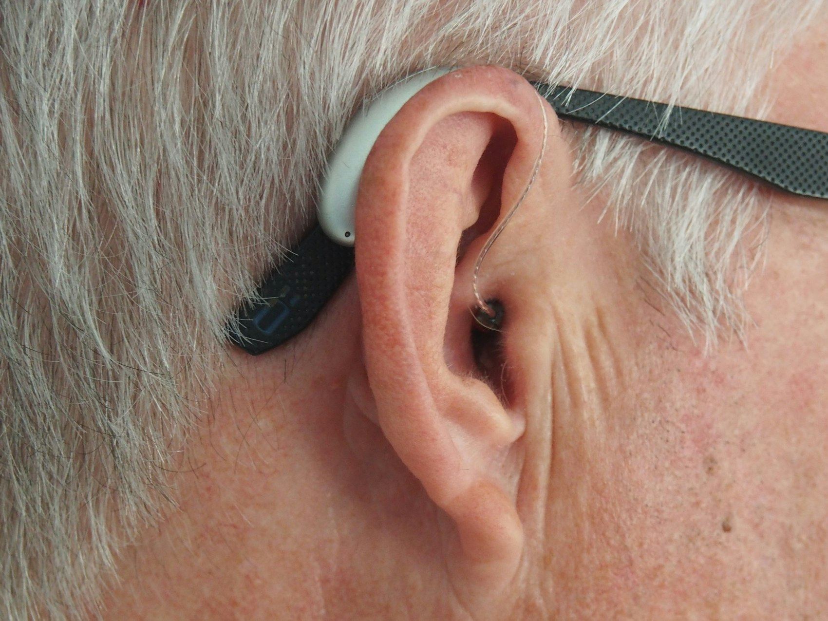 Close-up of a hearing aid fitted behind an elderly person's ear.